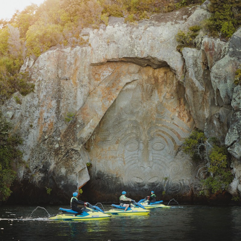 a group of people sitting on a rock next to water